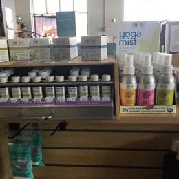Display of aromatherapy products: essential oils, mists, and candles on a wooden shelf in a store.