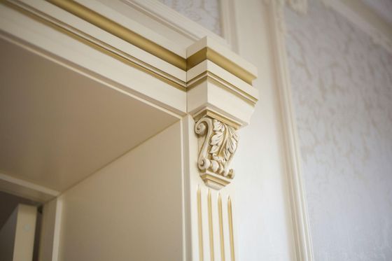 Professional painter in white overalls painting an interior wall white.