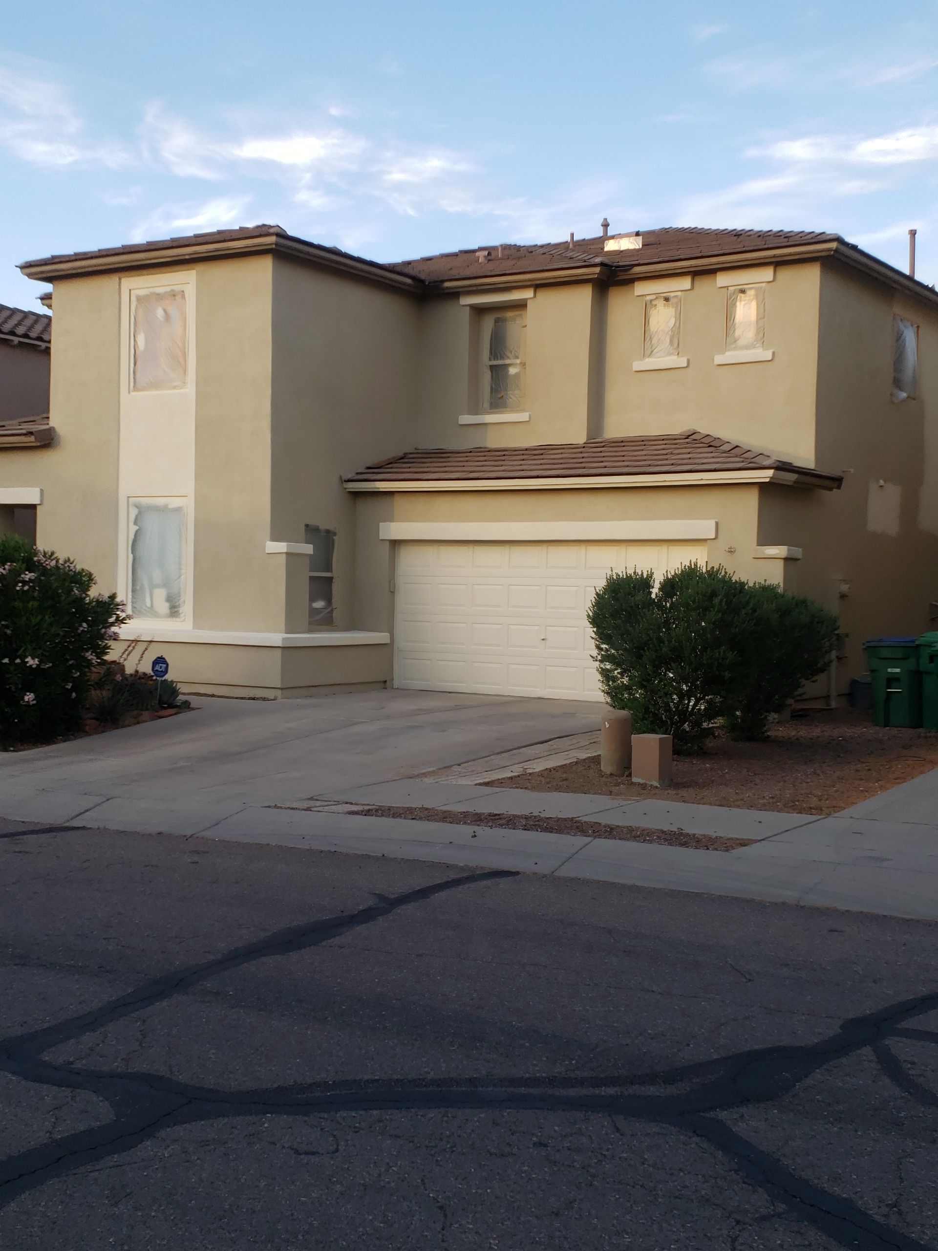 Exterior view of a beige stucco house with driveway and landscaped front yard.