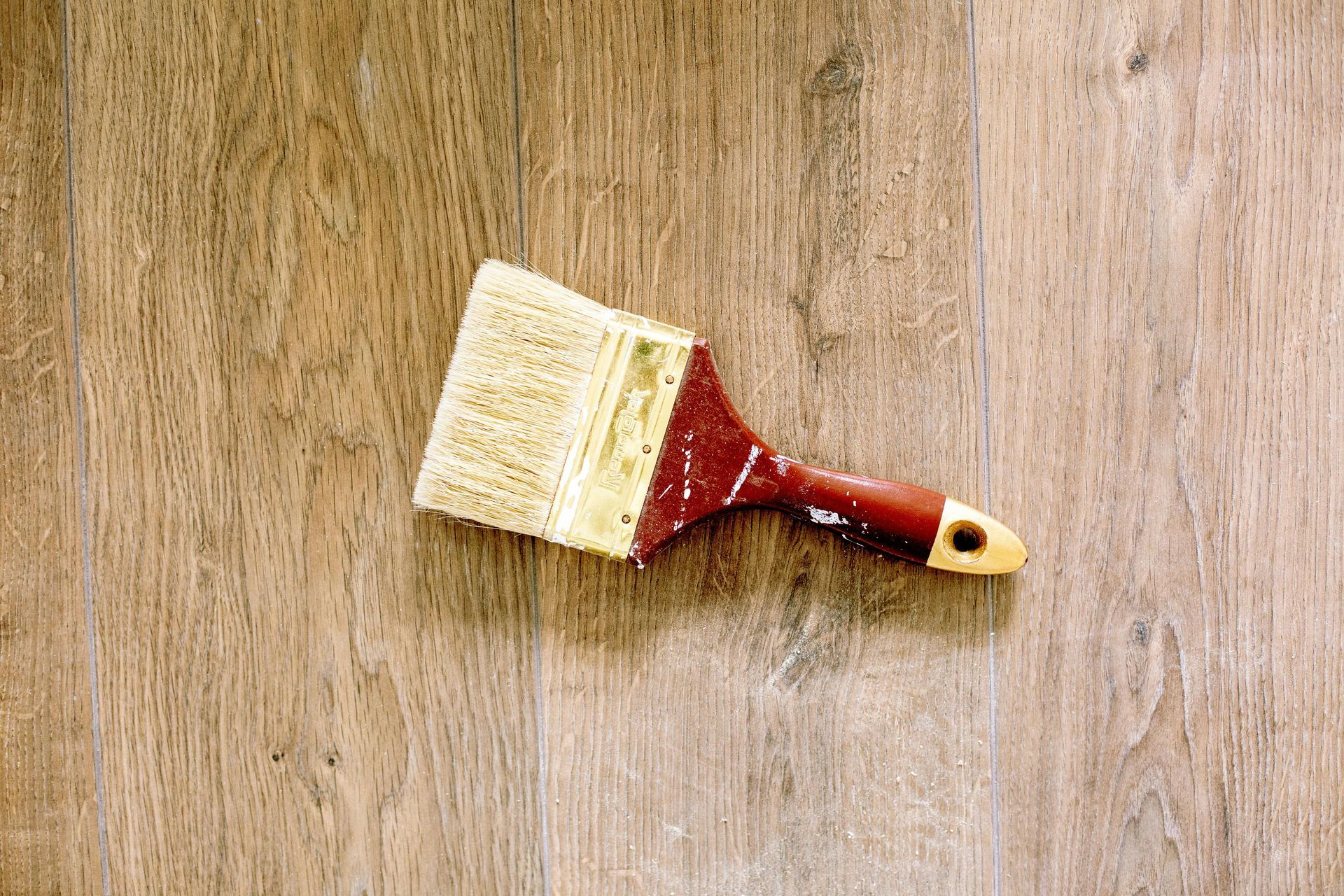 Paintbrush resting on wooden floor after painting project by Green Valley Painters in Green Valley, AZ.