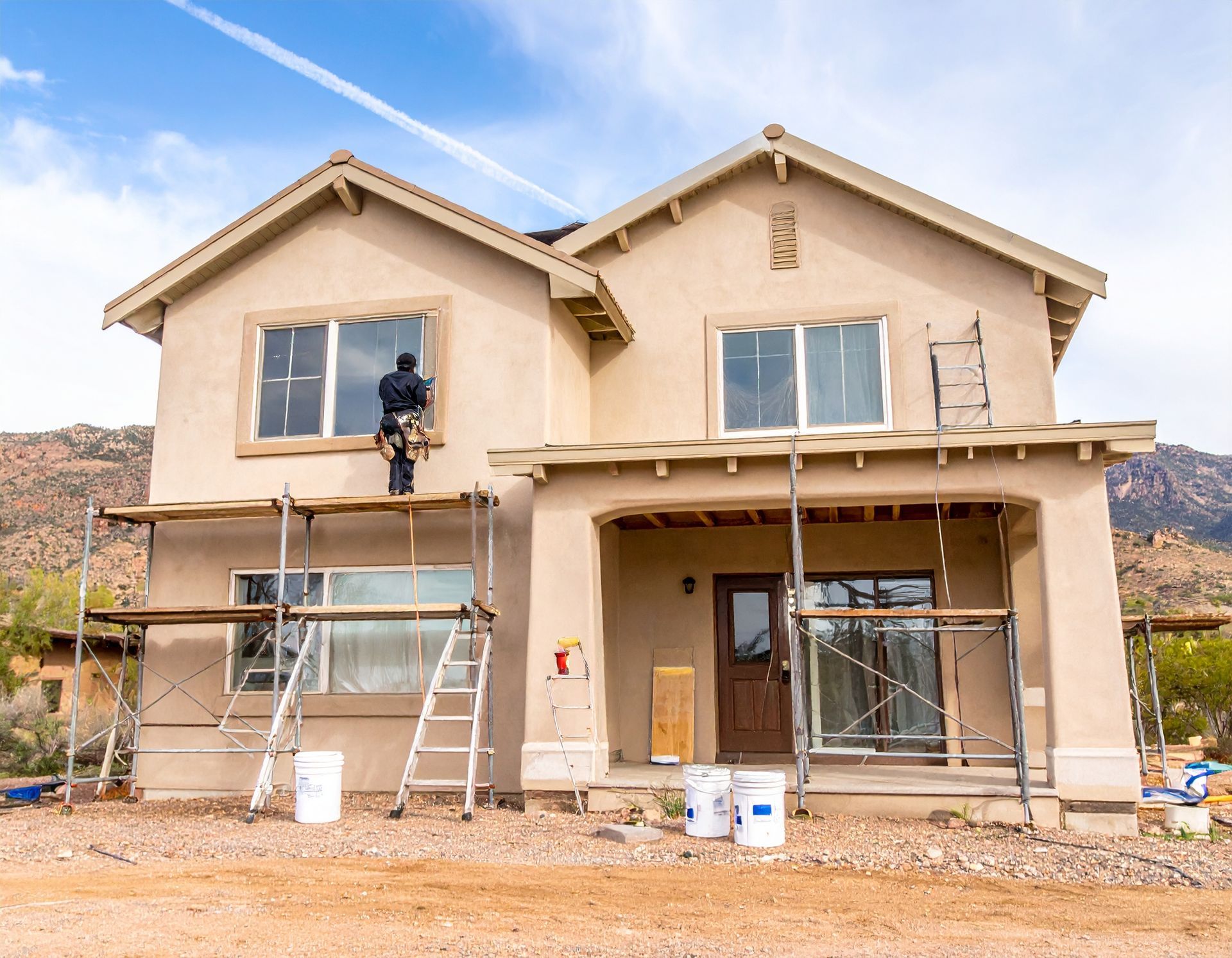 Painter on ladder working on stucco exterior home painting project in Green Valley, Arizona.