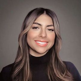 Team member Alejandra Coto, with long brown hair, smiling, wearing a black turtleneck.