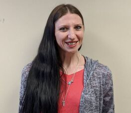 A woman with dark hair who is dressed professionally and smiling