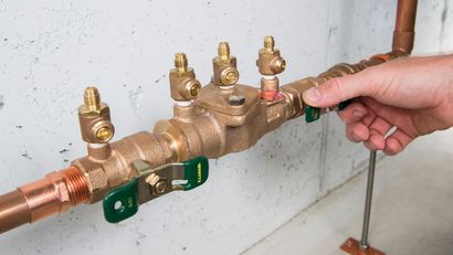 Pool pump and plumbing equipment with white PVC pipes and orange valves on a concrete pad.