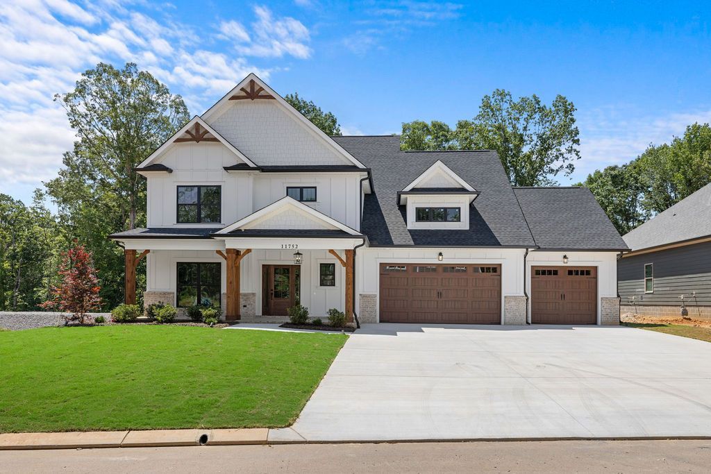 A large white house with two garages and a large driveway.