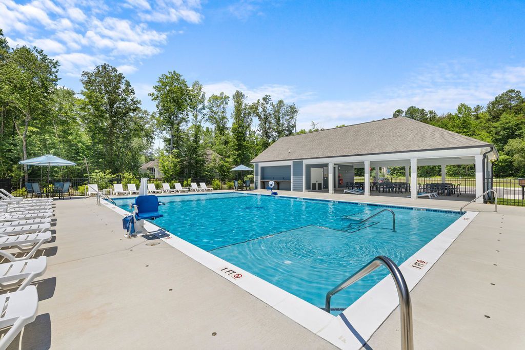There is a large swimming pool in the middle of a park.