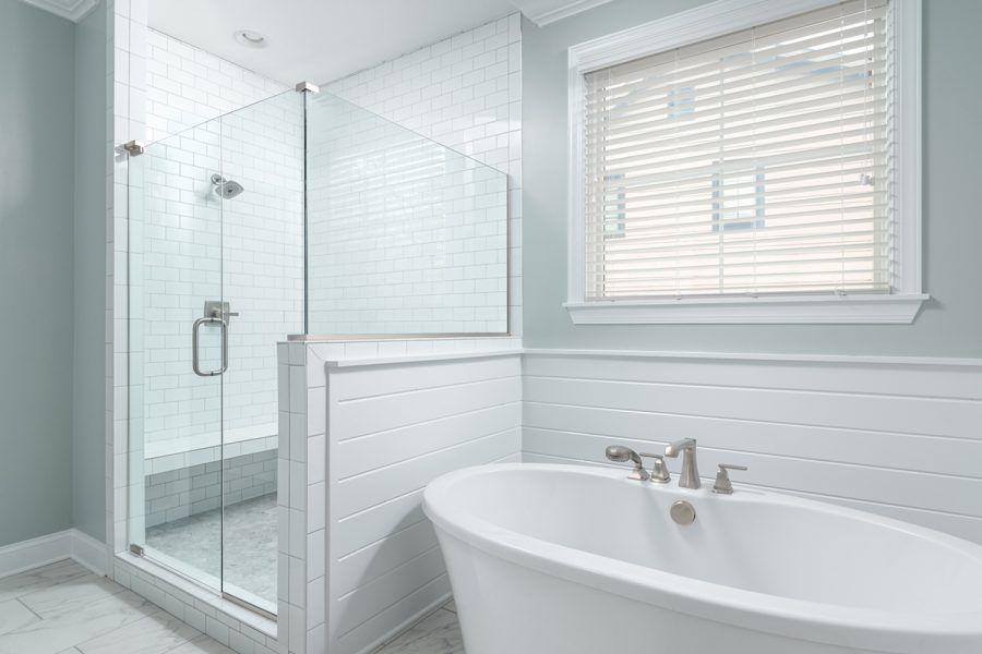 A bathroom with a tub , shower , and window.