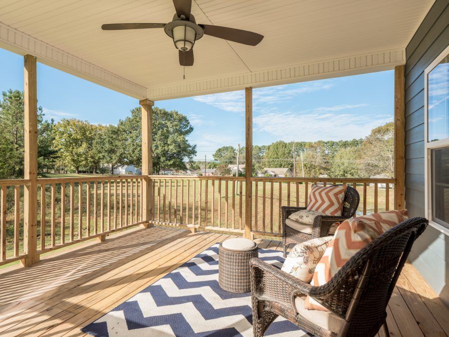 There is a ceiling fan on the porch of a house.