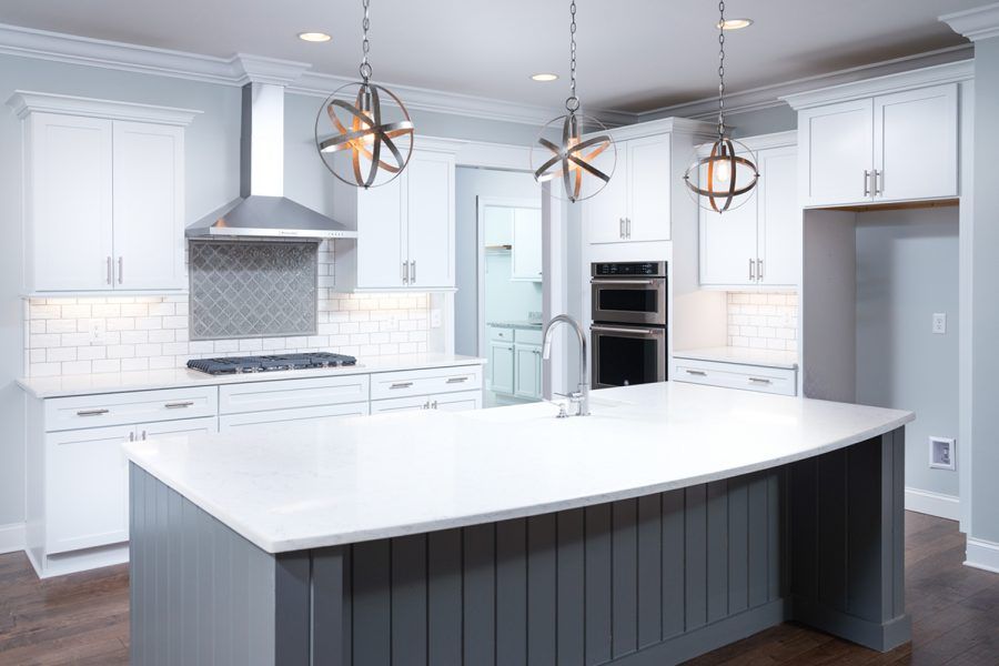 A kitchen with white cabinets and a large island in the middle.