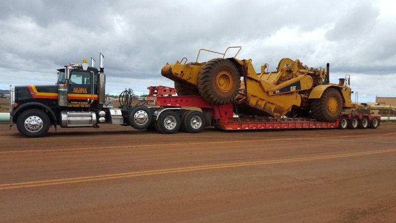 Truck transporting earth moving machine