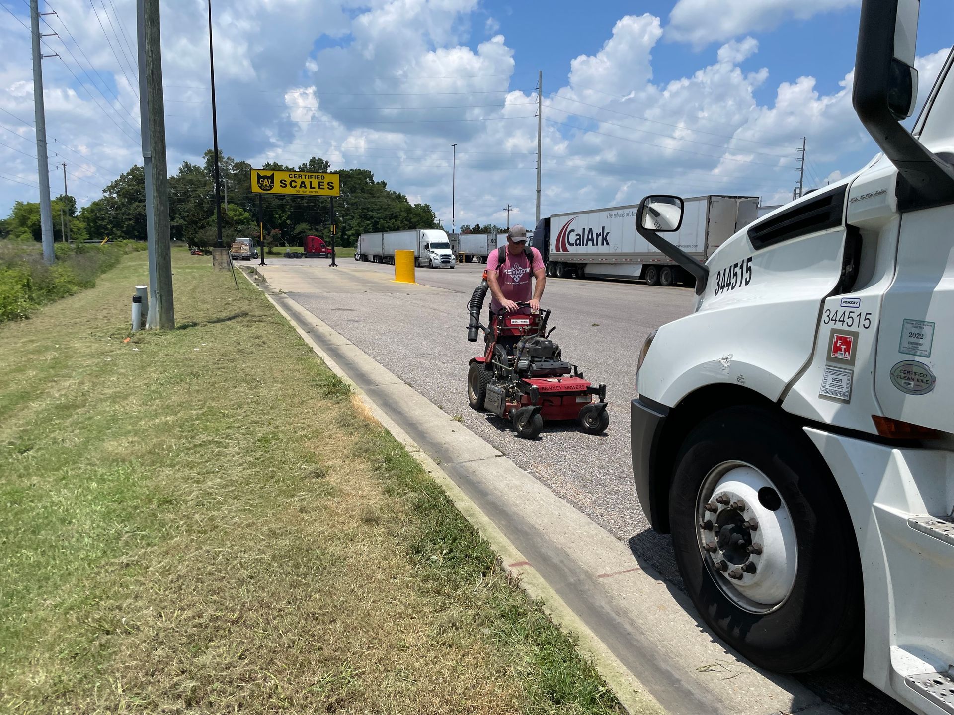 A man is riding a lawn mower next to a truck.