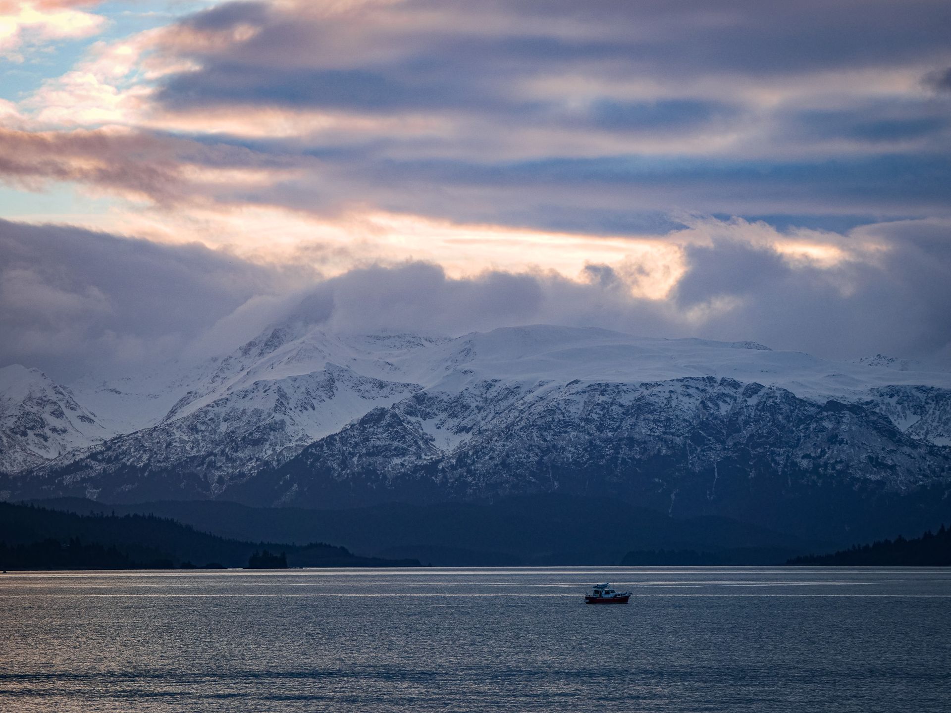 A boat is floating on top of a body of water with mountains in the background.