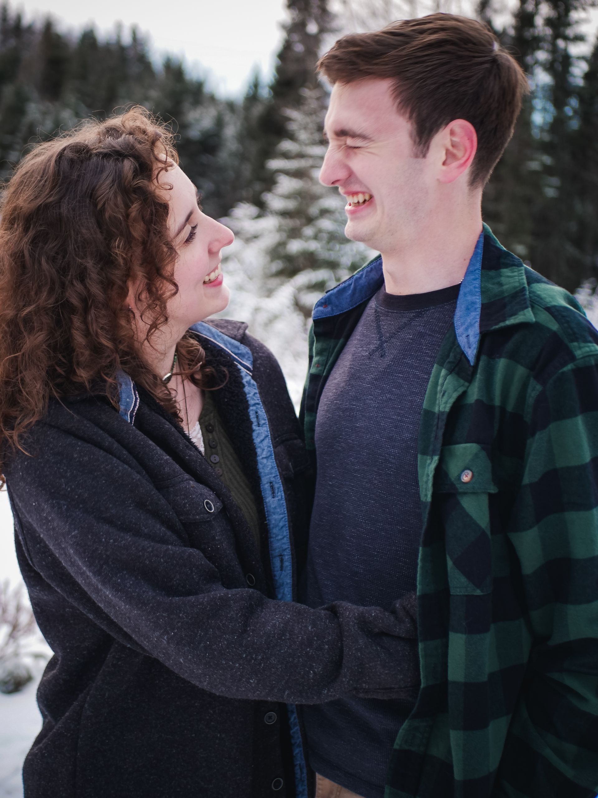 A man and a woman are looking at each other in the snow.