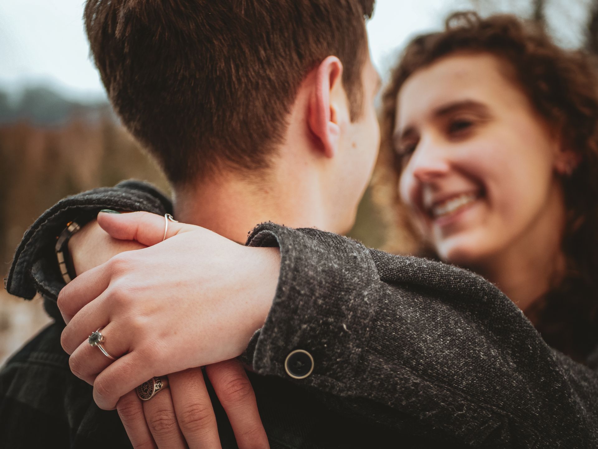 A woman is hugging a man with a ring on her finger.