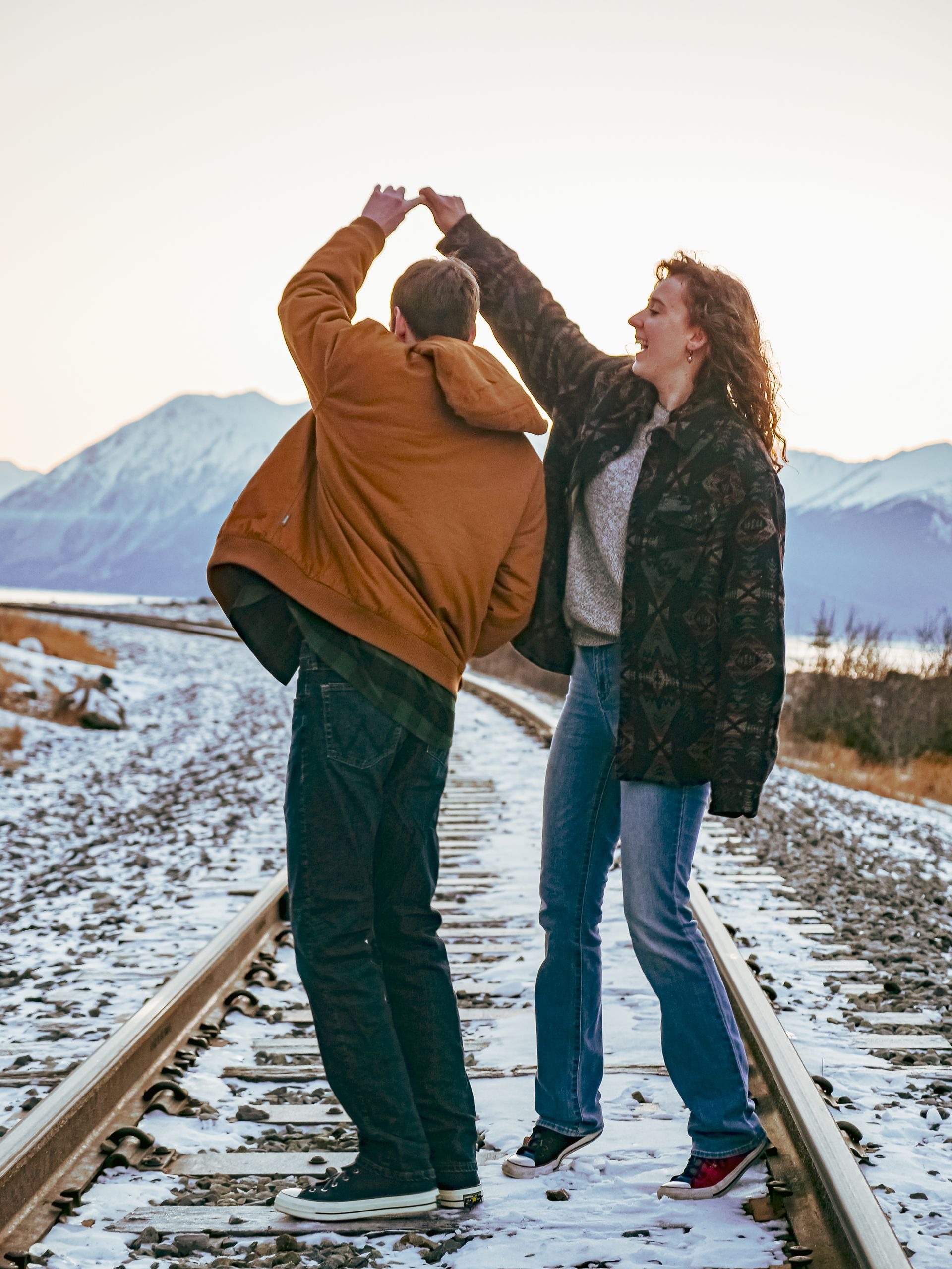A man and a woman are standing on train tracks in the snow.