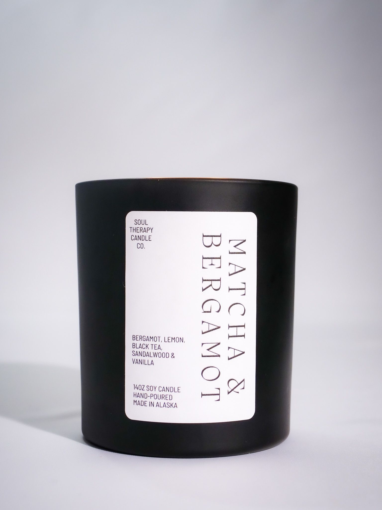 A black candle with a white label that says majaan bergamot