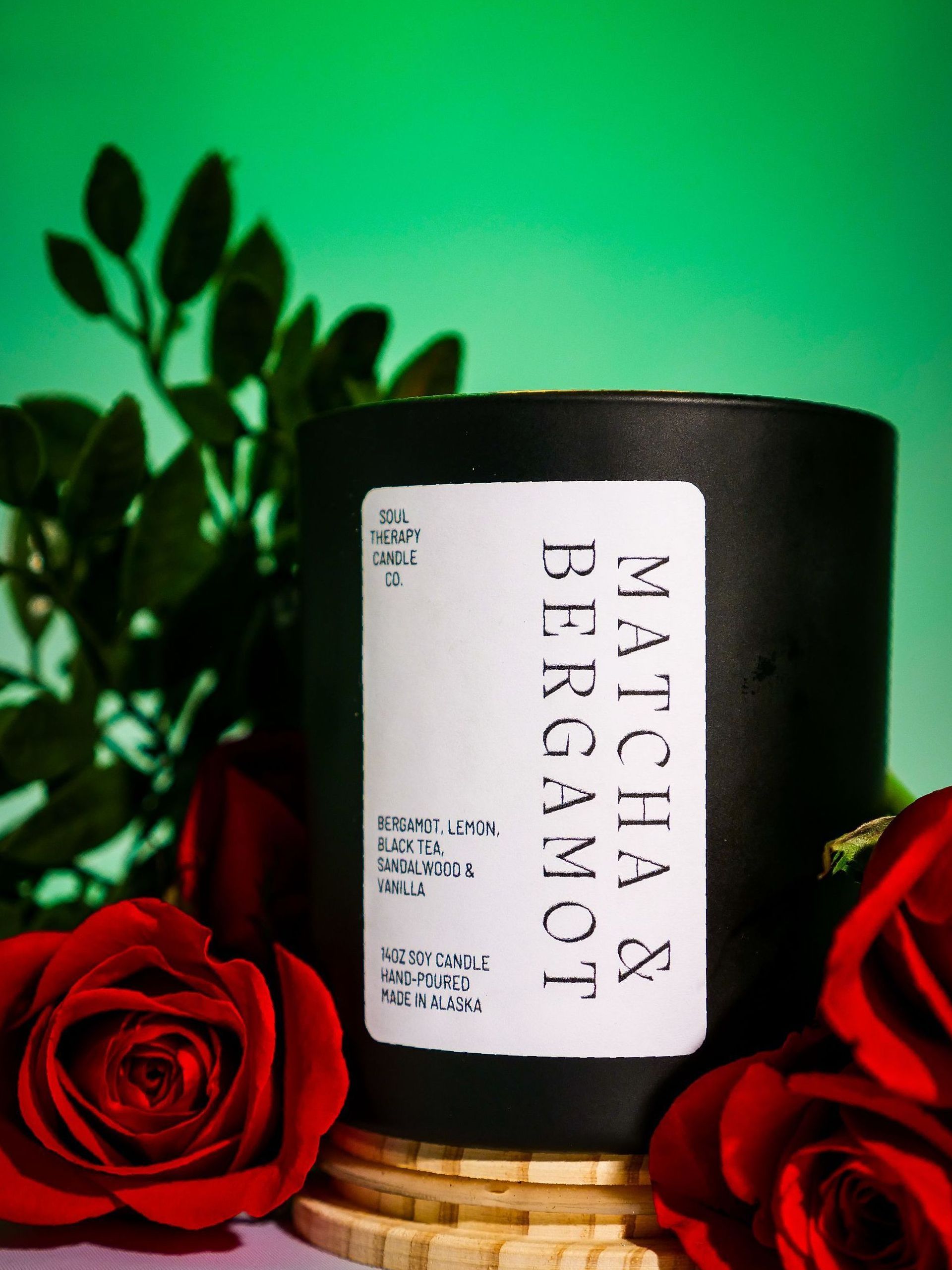 A black candle with a white label that says matcha bergamot