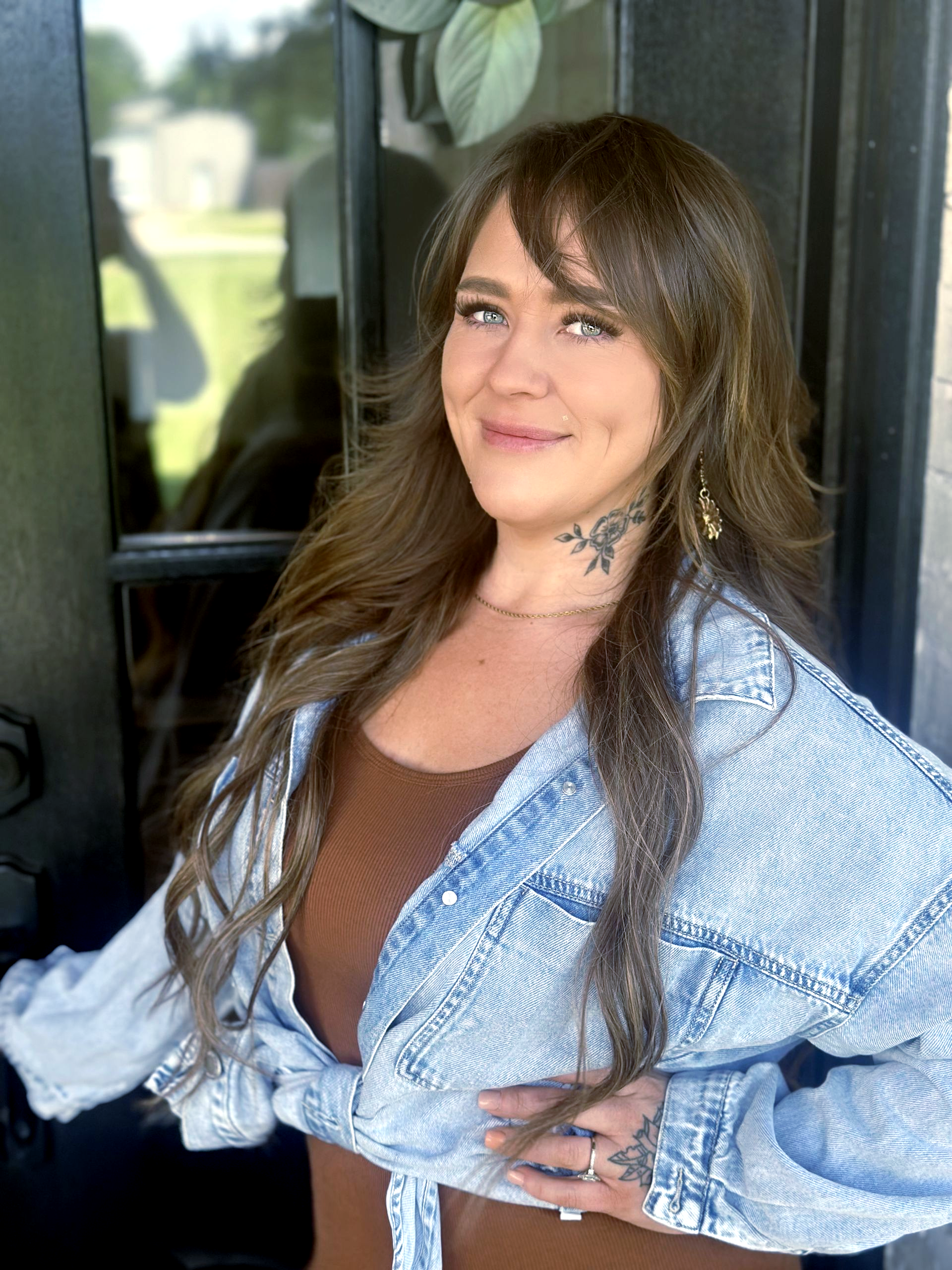 Person working at a wooden desk, with books, plants, and a vase; minimalist, bright interior.
