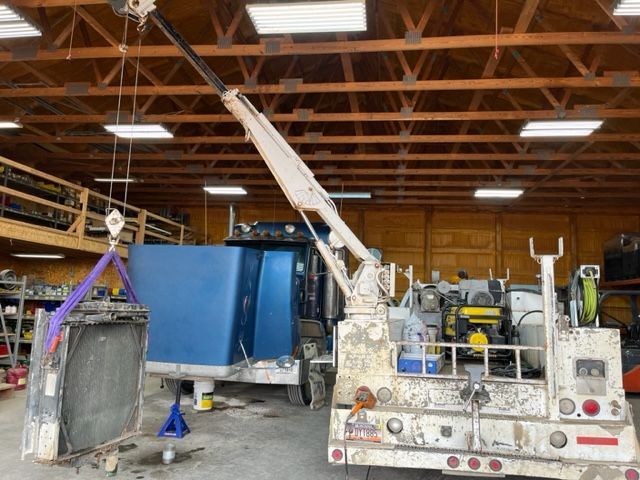 A truck with a crane attached to it is in a garage.