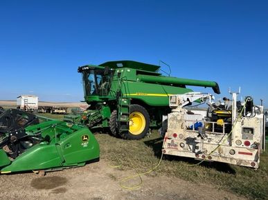 A john deere combine harvester is being towed by a tow truck