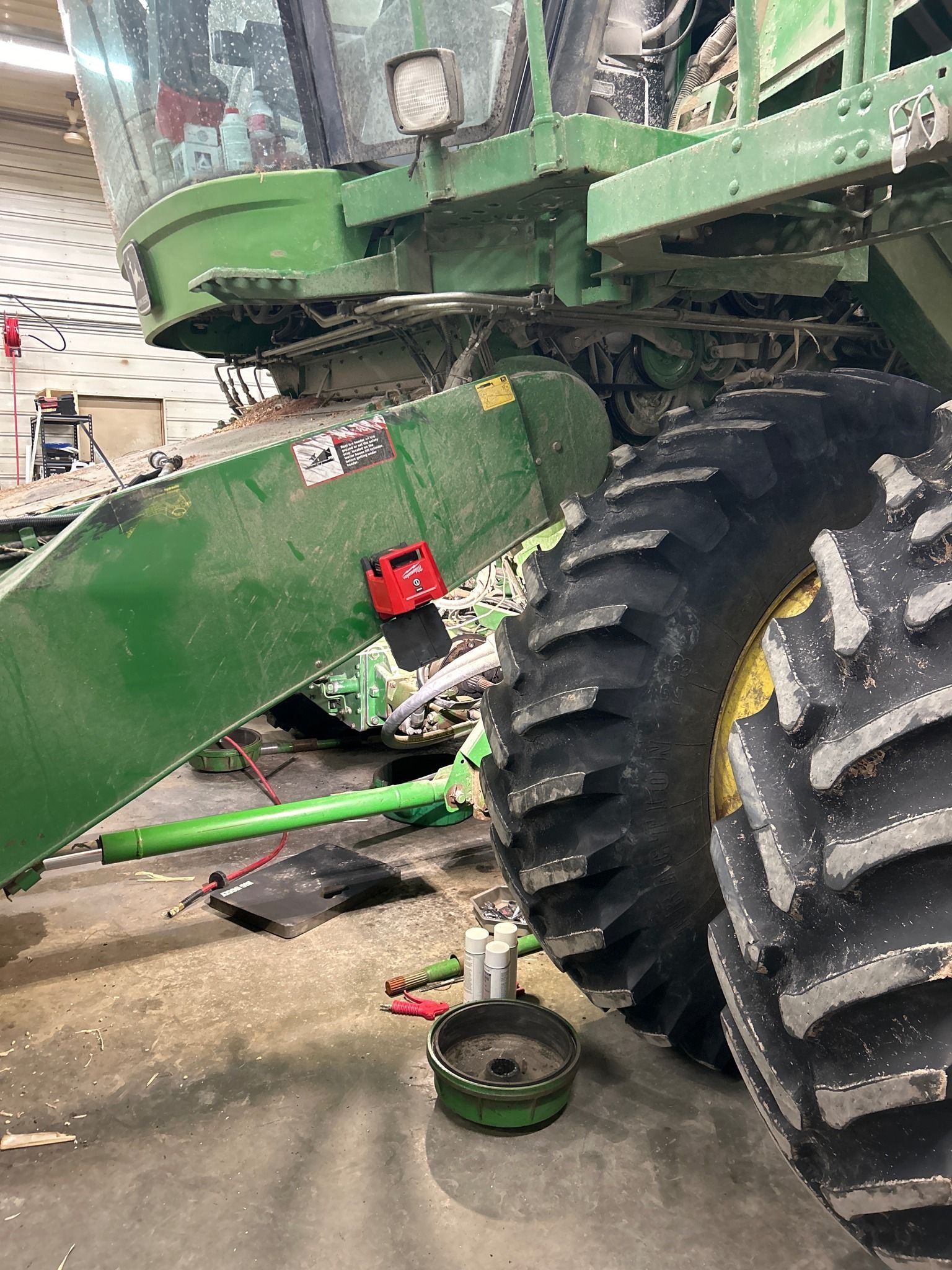 A green john deere combine harvester is sitting in a garage.