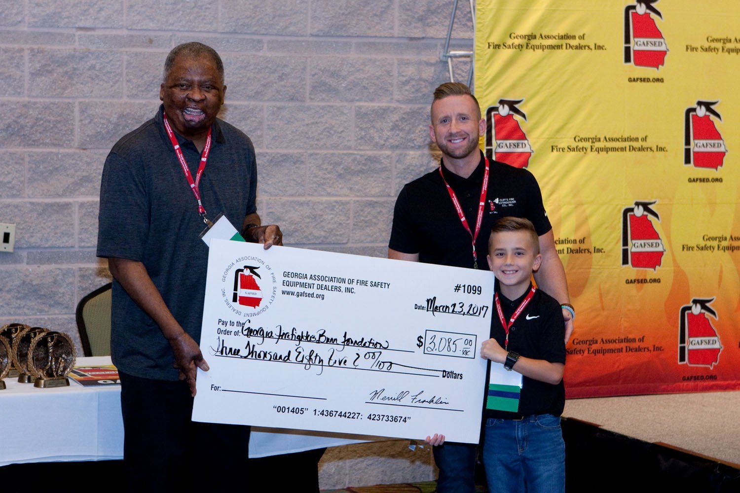 Two men and a boy are holding a large check