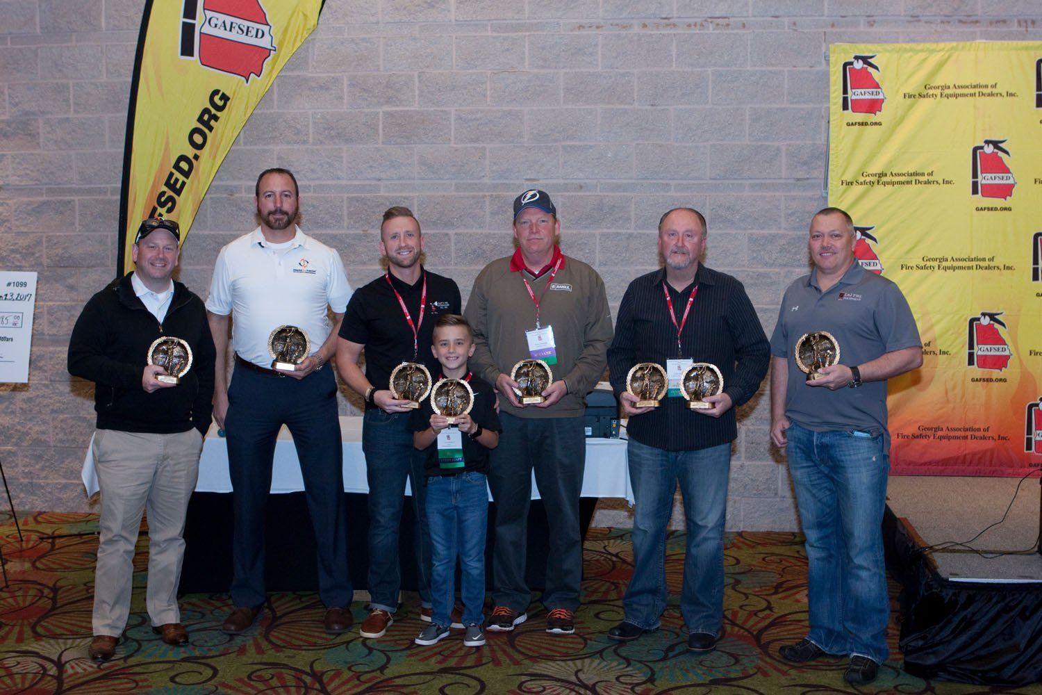 A group of men are posing for a picture while holding trophies