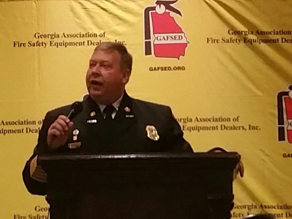 A man stands at a podium in front of a sign that says georgia association of fire safety equipment dealers