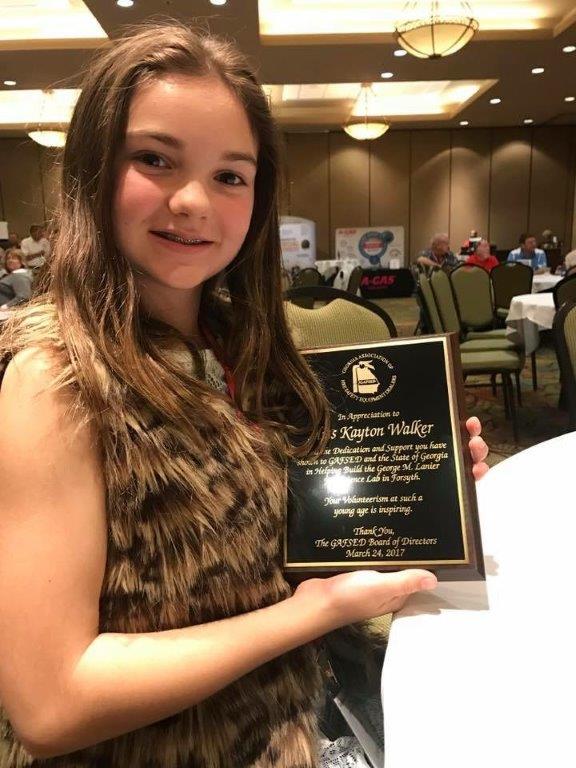A young girl is holding a plaque in a room.