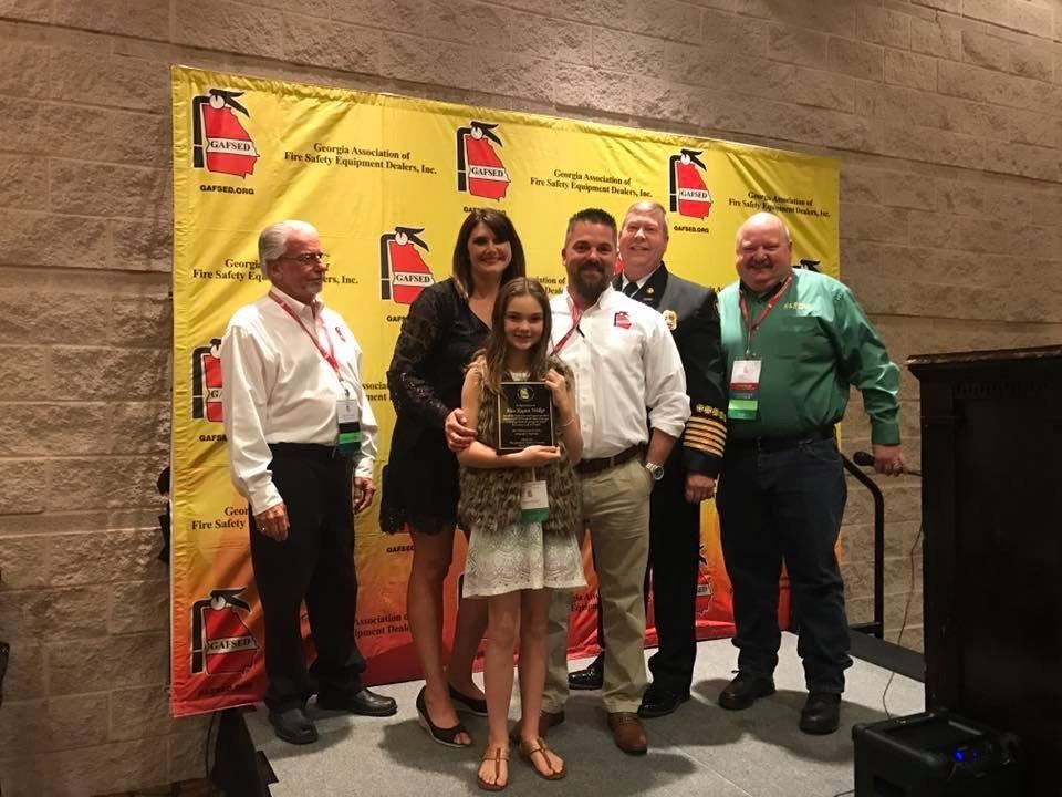 A group of people standing in front of a wall with fire extinguishers on it