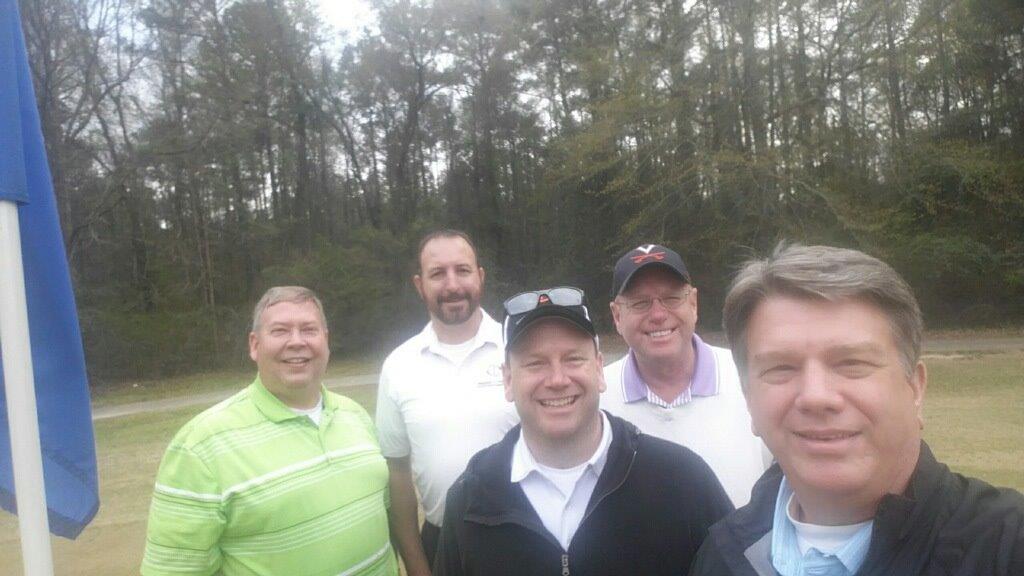 A group of men are posing for a picture on a golf course.