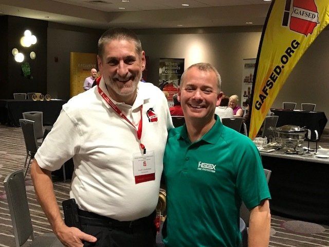 Two men are posing for a picture in front of a sign that says gafsed.org