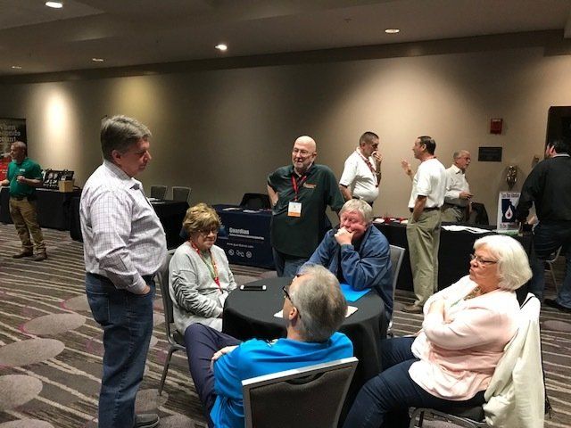 A group of people are sitting at tables in a room talking to each other.
