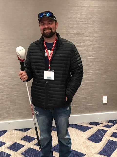 A man in a black jacket is holding a baseball bat