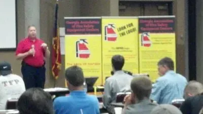 A man in a red shirt is giving a presentation to a group of people