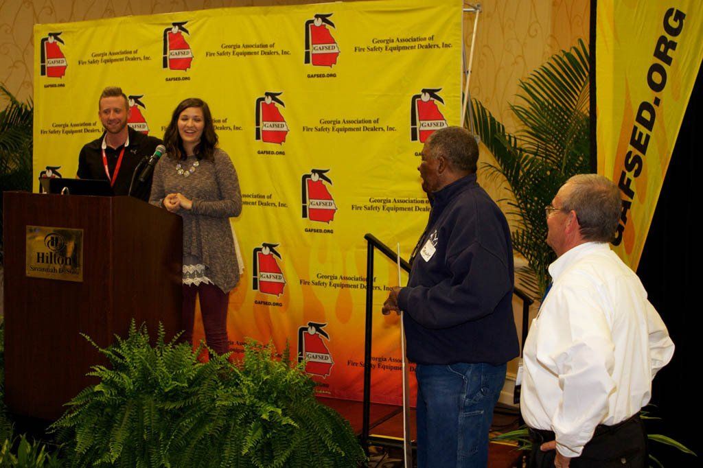 A group of people standing in front of a yellow wall with fire extinguishers on it