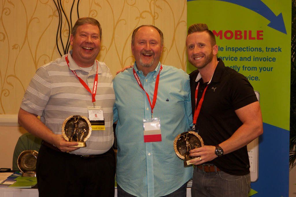 Three men are posing for a picture in front of a mobile sign