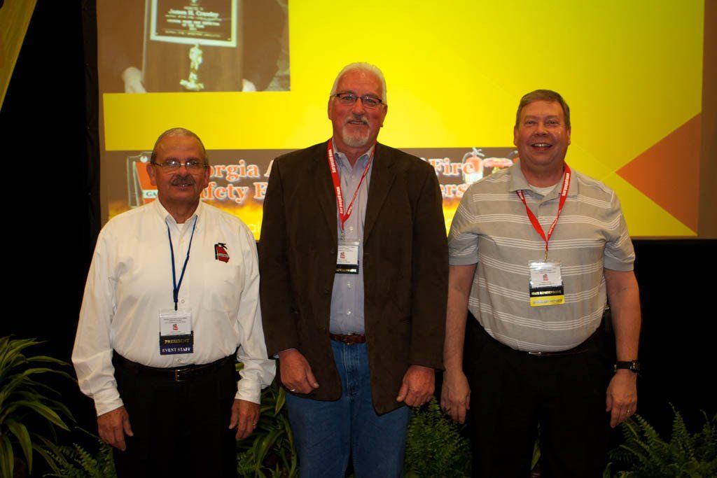Three men are posing for a picture in front of a yellow screen