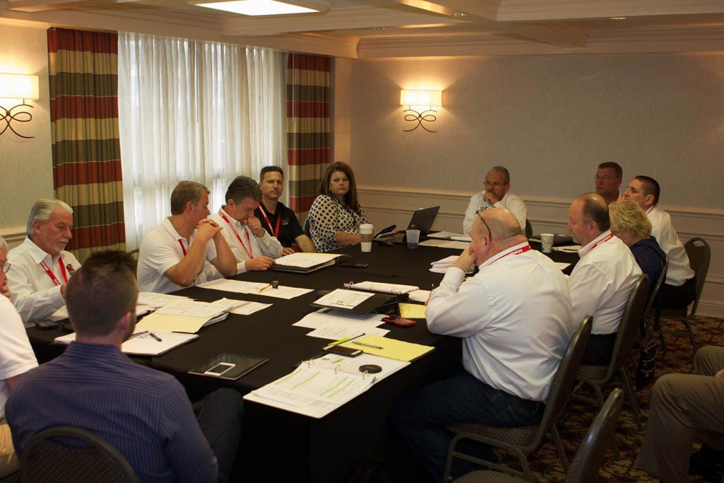 A group of people are sitting around a long table in a conference room.