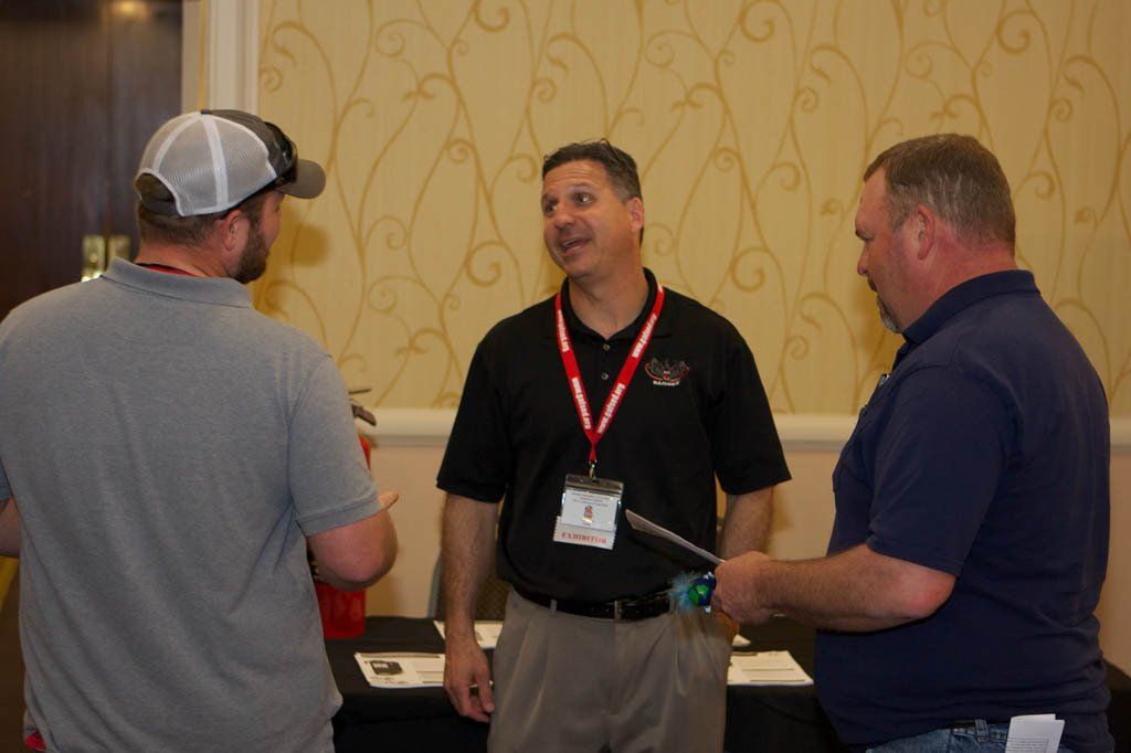 Three men are standing in a room talking to each other.