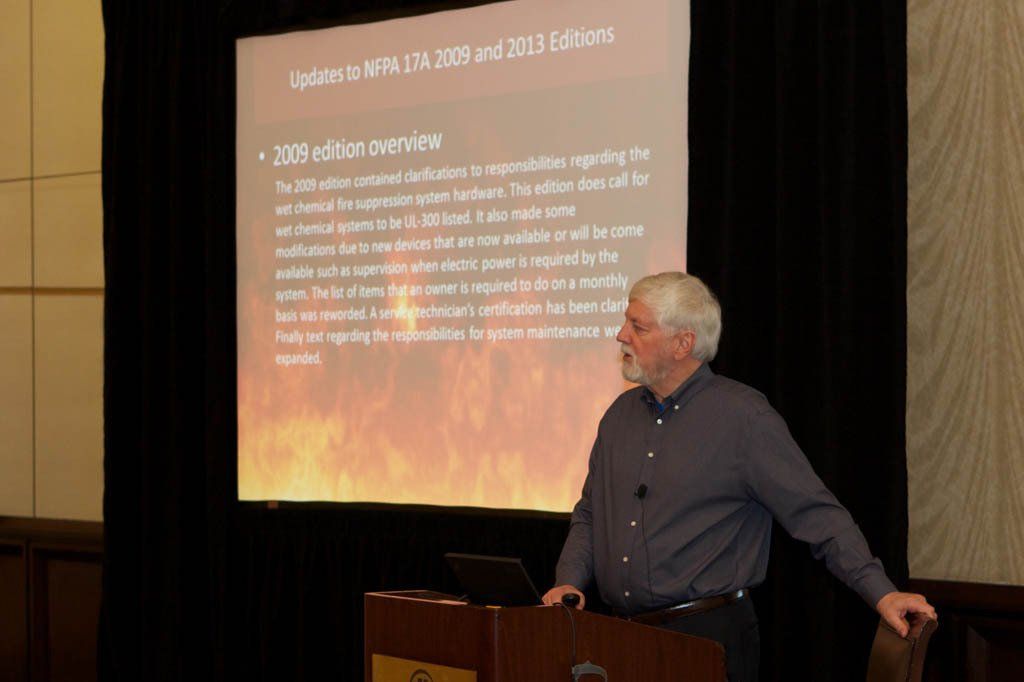 A man stands at a podium in front of a screen that says updates