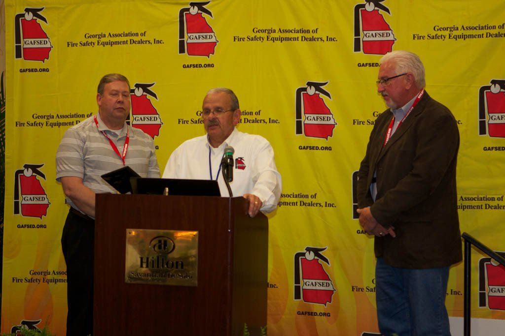 Three men standing in front of a podium that says hilton on it