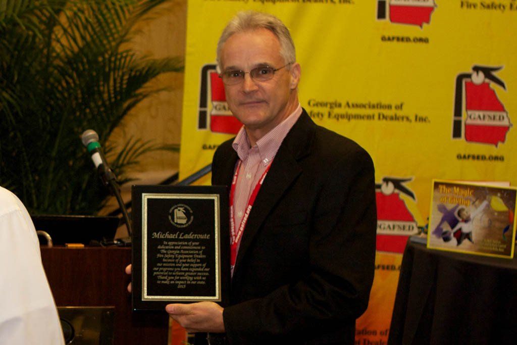 A man in a suit is holding a plaque that says michael collins