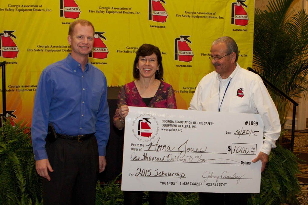 Two men and a woman holding a large check