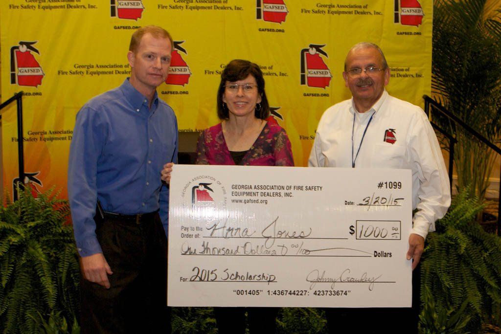 Two men and a woman holding a check that says 2015 on it