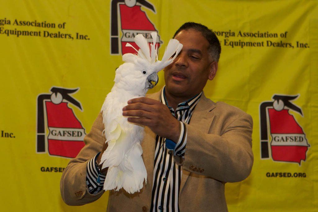 A man holding a white bird in front of a sign that says gafsed