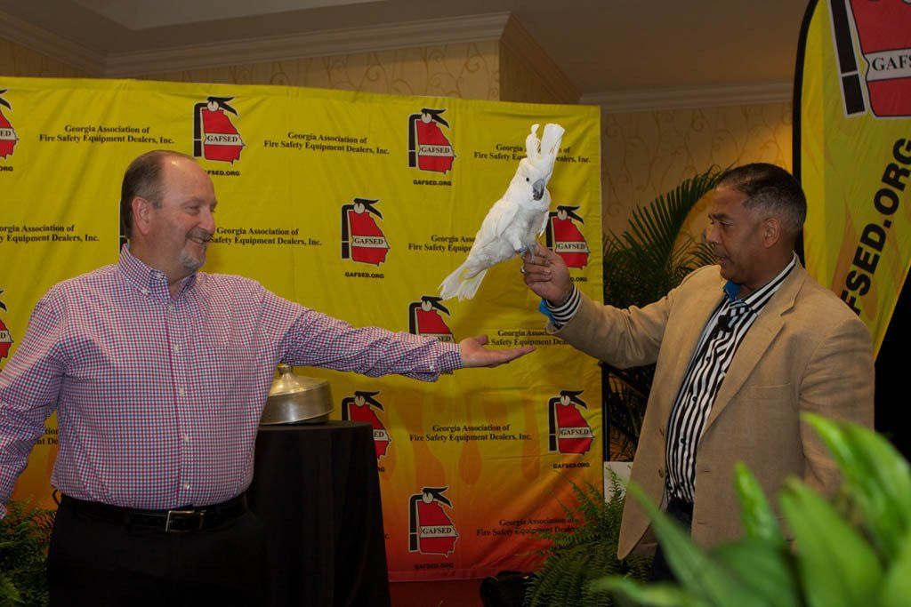 Two men standing in front of a wall with fire extinguishers on it