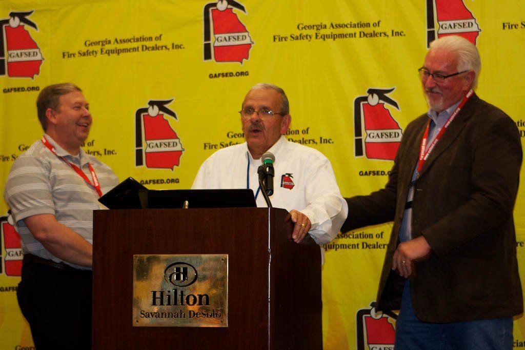 Three men standing in front of a podium that says hilton