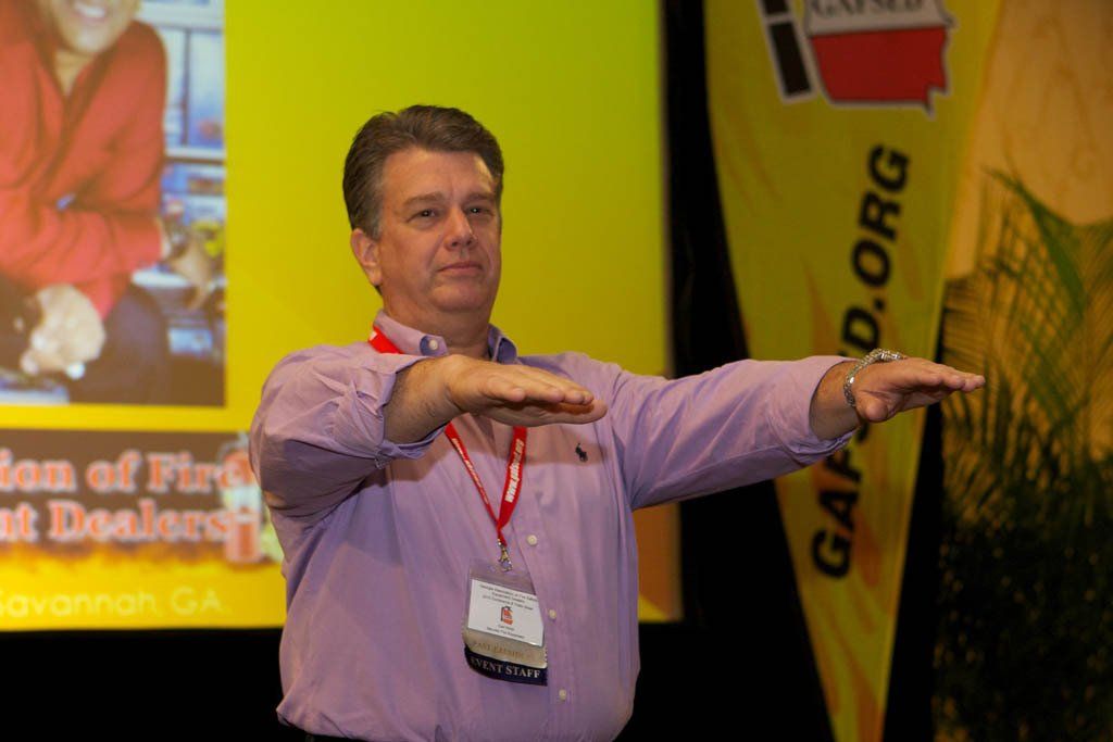 A man in a purple shirt is standing in front of a yellow banner that says gapd.org