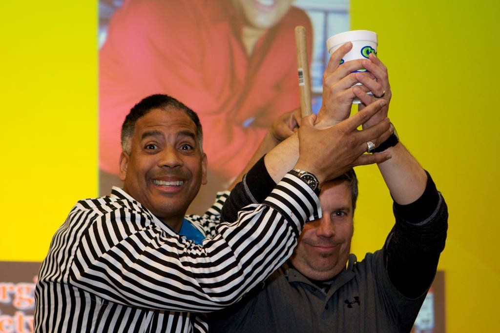 A man in a striped shirt is holding a cup in his hand